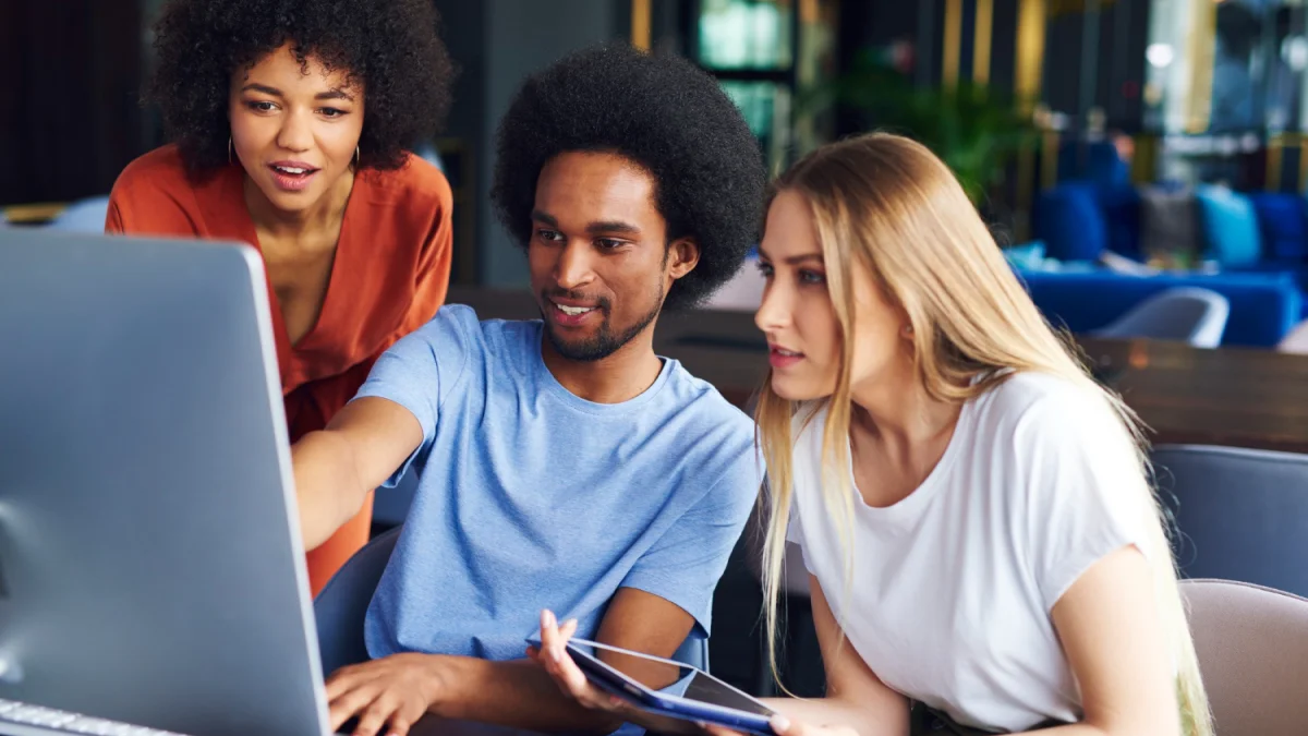 3 office employees looking at desktop monitor screen